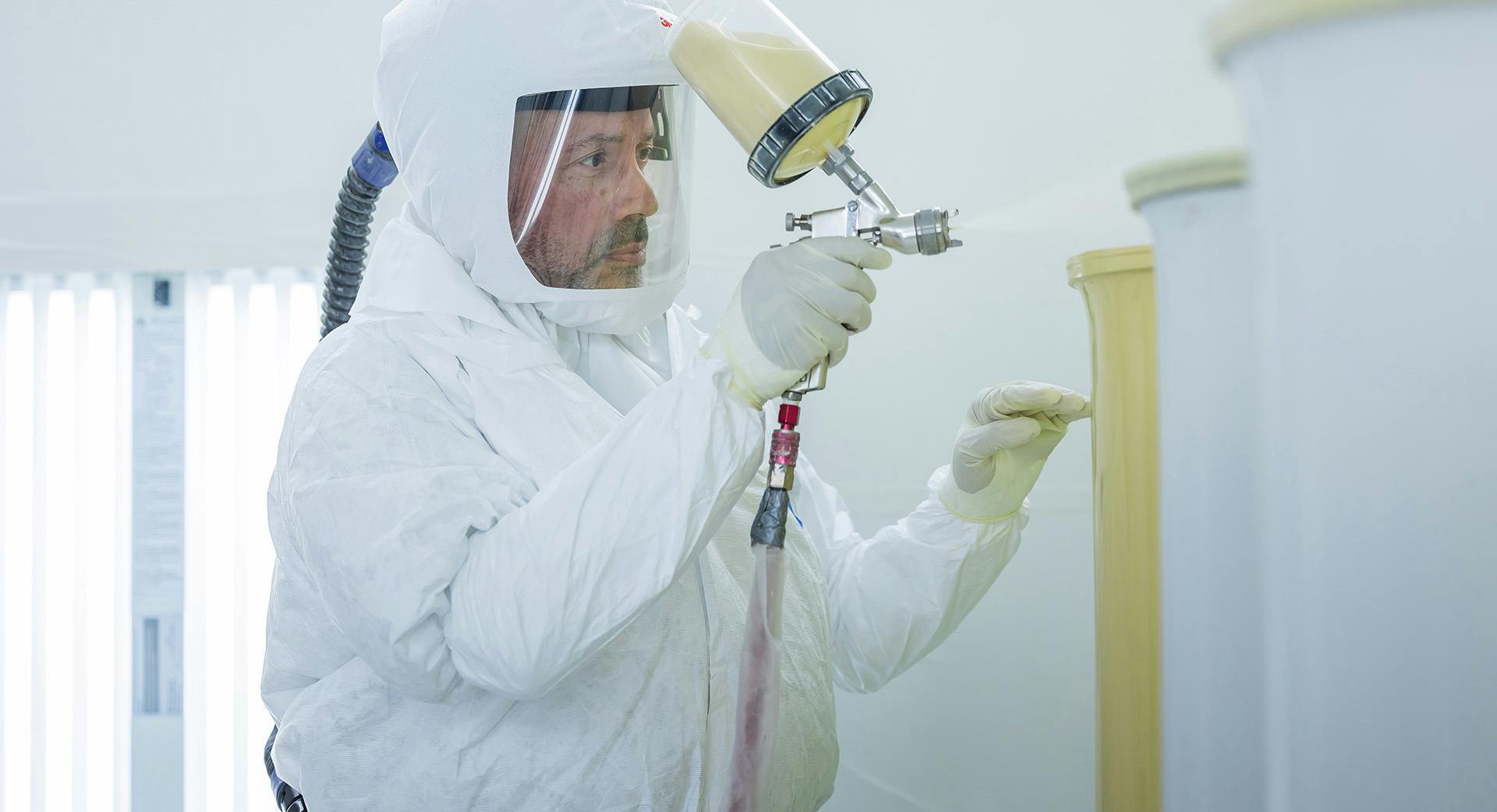 Engineer using a paint sprayer to paint components