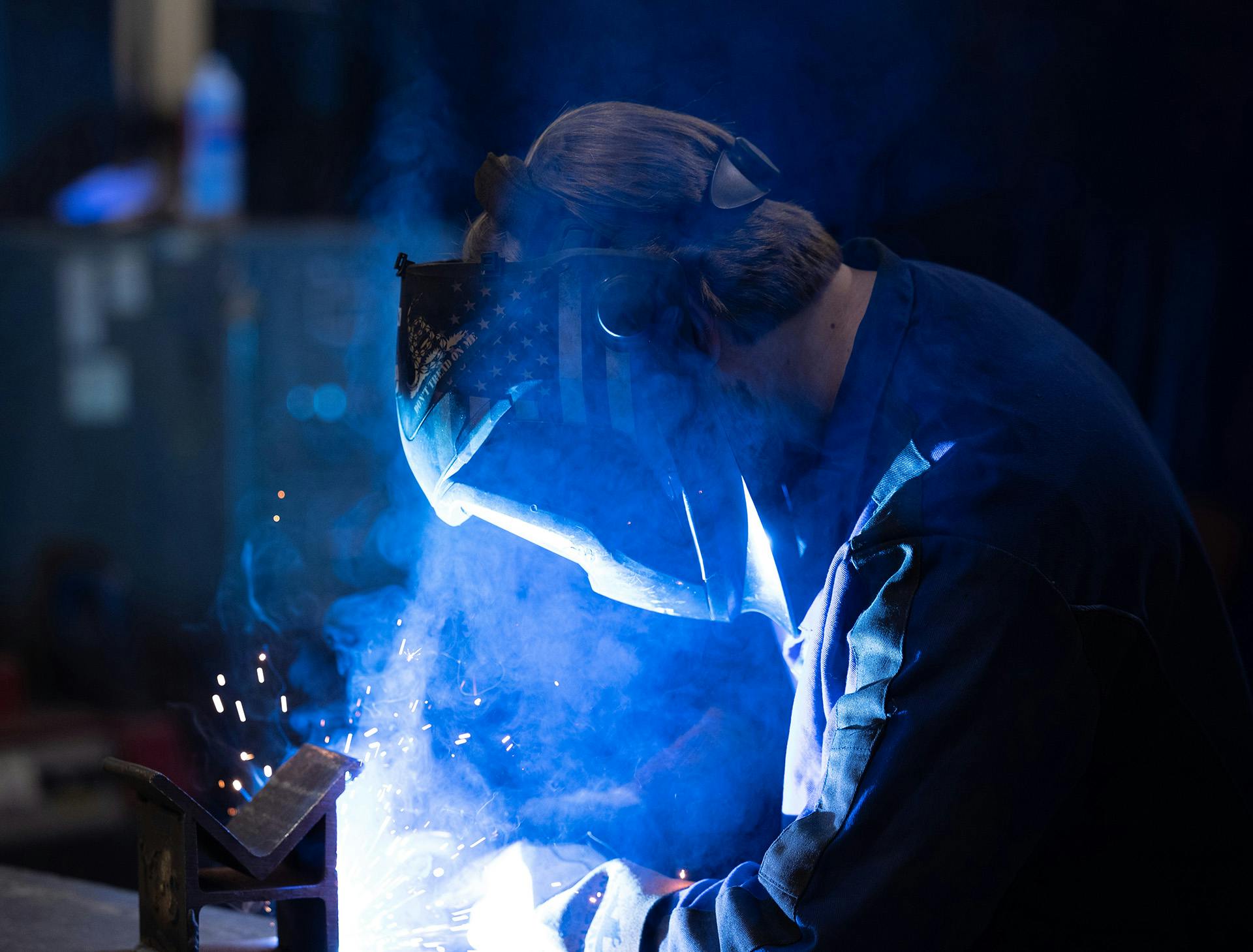 Engineer wearing protective helmet and mask while welding a product