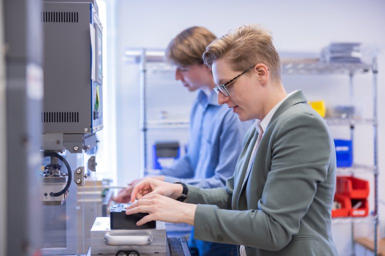 Two engineers working together at a machine