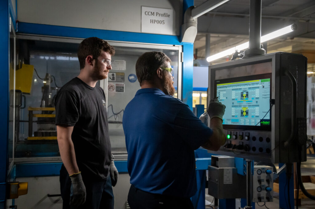 Two employees working with a machine.