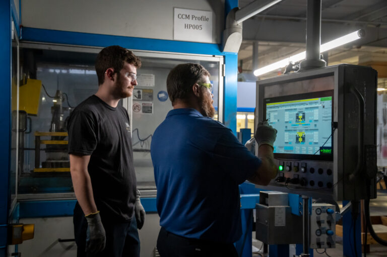 Two employees working with a machine.